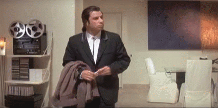 John Travolta looks around the room, puzzled.